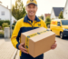 Postbote der DHL hält einen Karton der "Ihr Logo" auf dem Klebeband stehen hat.